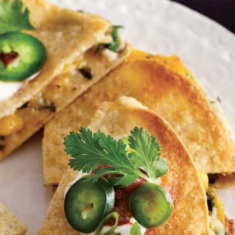Two quarters of mashed potato and cheese stuffed quesadillas on a white plate, garnished with sliced jalapenos.