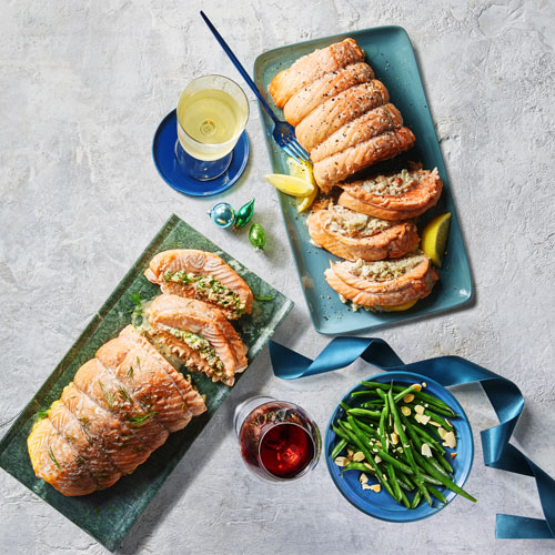 Stuffed salmon roasts on blue and green platters.