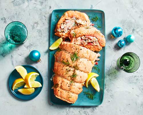 Turquoise platter with whole stuffed salmon roast, dill spigs and lemon wedges.