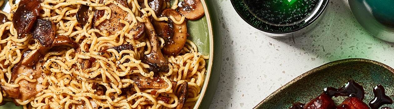 Blue bowl full of ramen noodles with mushrooms.