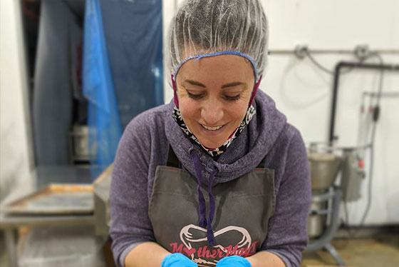 Nada Choufi in food safe garb holding handfuls of chickpeas on her factory floor.