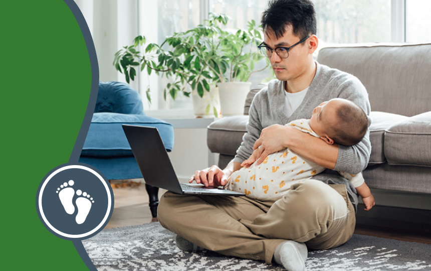 Parent holding baby while typing on a laptop