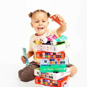 Young child stacking packs of Cerebelly baby food puree and Cerebelly smart bars into a tower