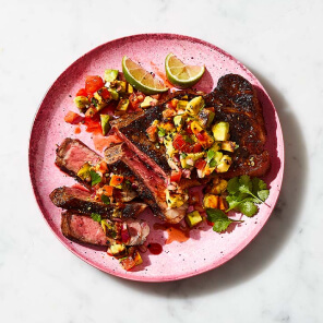 Pink plate topped with slices of Sterling Silver Striploin grilling steak and grilled guacamole on top.