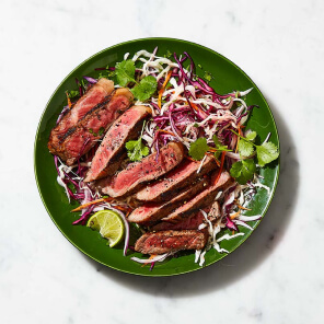 Green plate topped with slices of Sterling Silver grilling steak and a fresh Latin-American-style slaw.