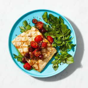 Bright blue plate topped with grilled mahi mahi, summer herb sauce and heirloom tomato salsa.