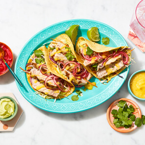 Turquoise platter topped with three mahi mahi tacos, quick pickled onions, mango jalepeno sauce and an avocado-lime crema.