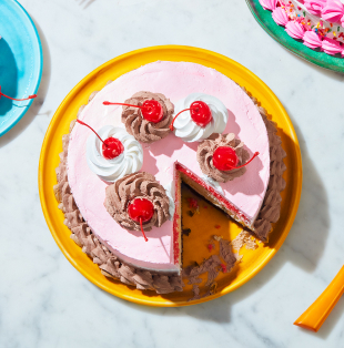Triple-layer Neapolitan cake iced in white and pink with a chocolate border, sitting atop a blue dessert plate with a fork next to it.