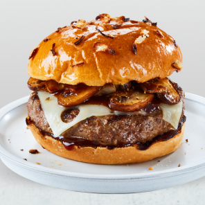 Mushroom and Swiss Cheeseburger with sauteed onions on an onion bun sitting on a white countertop.