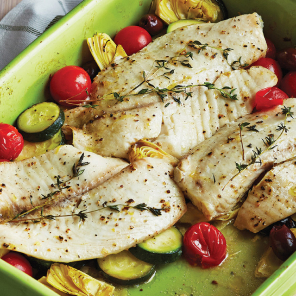 White fish fillets in a green baking dish with cherry tomatoes, herbs, zucchini and artichoke hearts.