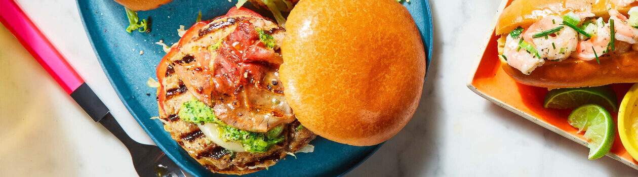 Homemade sausage burger on blue plate dressed with lettuce and a tomato salsa.