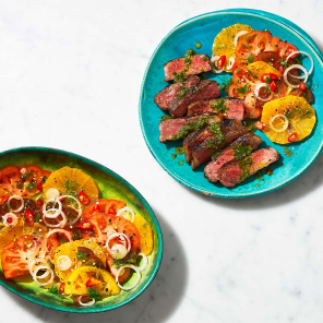 Turquoise plate with a grilled Sterling Silver Beef Striploin Grilling Steak with a side of heirloom tomato salad.