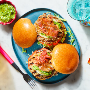 Homemade sausage burger on blue plate dressed with lettuce and a tomato salsa. 