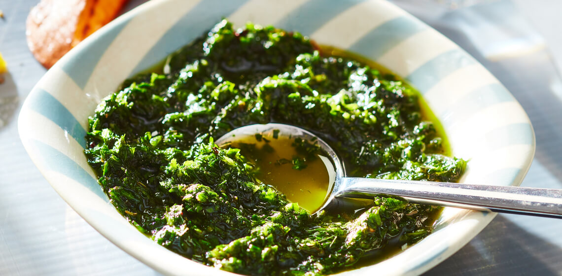 White and blue striped bowl filled with a fresh herb green sauce.