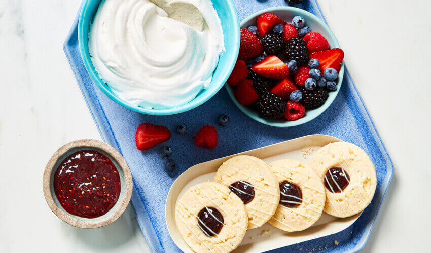 Layered vanilla pudding and blueberry sugar cookie trifle featuring fresh berries, strawberry jam, and a light whipped topping.