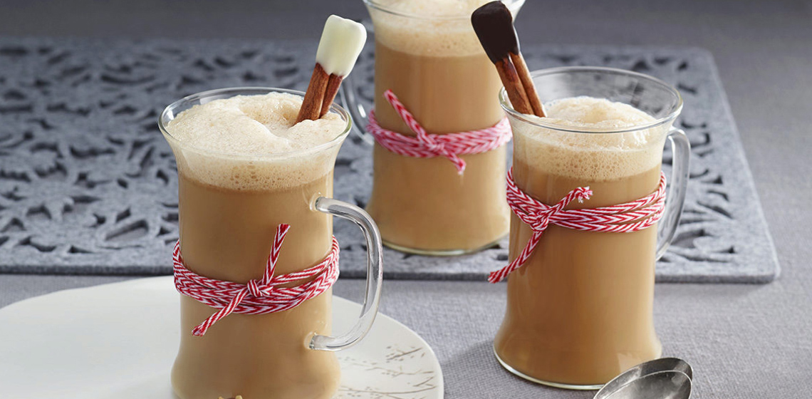 Three glass mugs filled with Gingerbread Almond Latte with a cinnamon stick poking out of the mug that’s been wrapped with red and white twine.