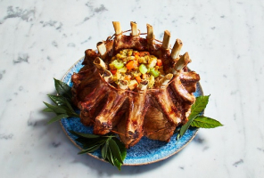 crown roast on plate stuffed with veggies on a blue and white platter.