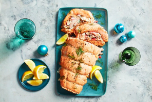 Turquoise platter with whole stuffed salmon roast, dill sprigs and lemon wedges.
