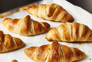 counter with parchment-lined cookie sheet of freshly baked butter croissants