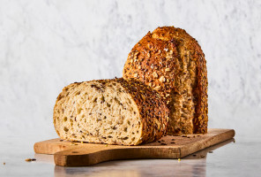Loaf of Artisan Prairie Harvest Bread cut in half on a cutting board