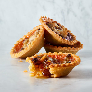 Four butter tarts stacked against each other on a marble background