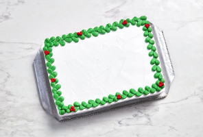 marble surface with rectangular white slab cake on silver sheet, with green and red holly buttercream edging and no centre decoration
