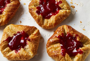 Baked danishes with red fruit filling on a parchment-lined baking sheet