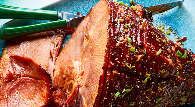 Oval light blue platter with Gochujang & Maple Glazed Spiral Ham with sesame seed and green onion garnish