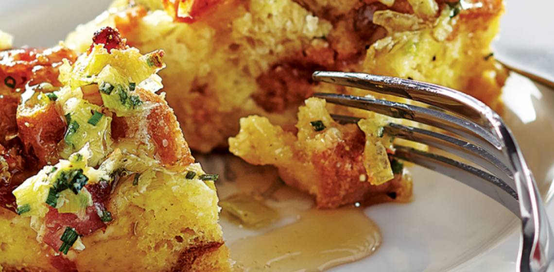 A white plate with a fork cutting through a piece of savoury panettone-based French toast.