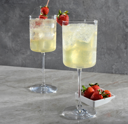 A gin-based drink in an ice-filled goblet starring Betty Buzz Sparkling Lemon Lime and garnished with strawberries on a pick.