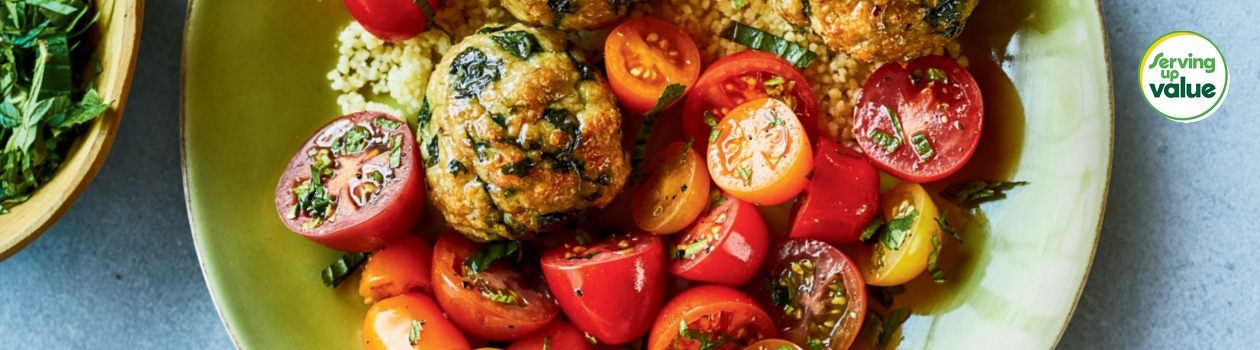 Bowl of turkey and spinach meatballs with sliced grape tomatoes and couscous