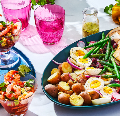 Table set with platters of food – niçoise salad, shrimp cocktails and melon granita glasses