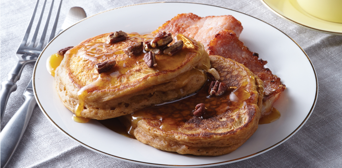Plate of sweet potato gingerbread pancakes with cup of tea in background