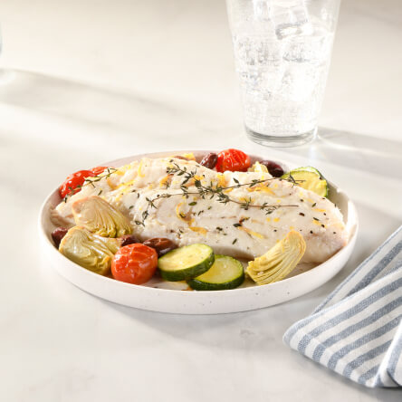 White haddock on plate with side of grilled vegetables