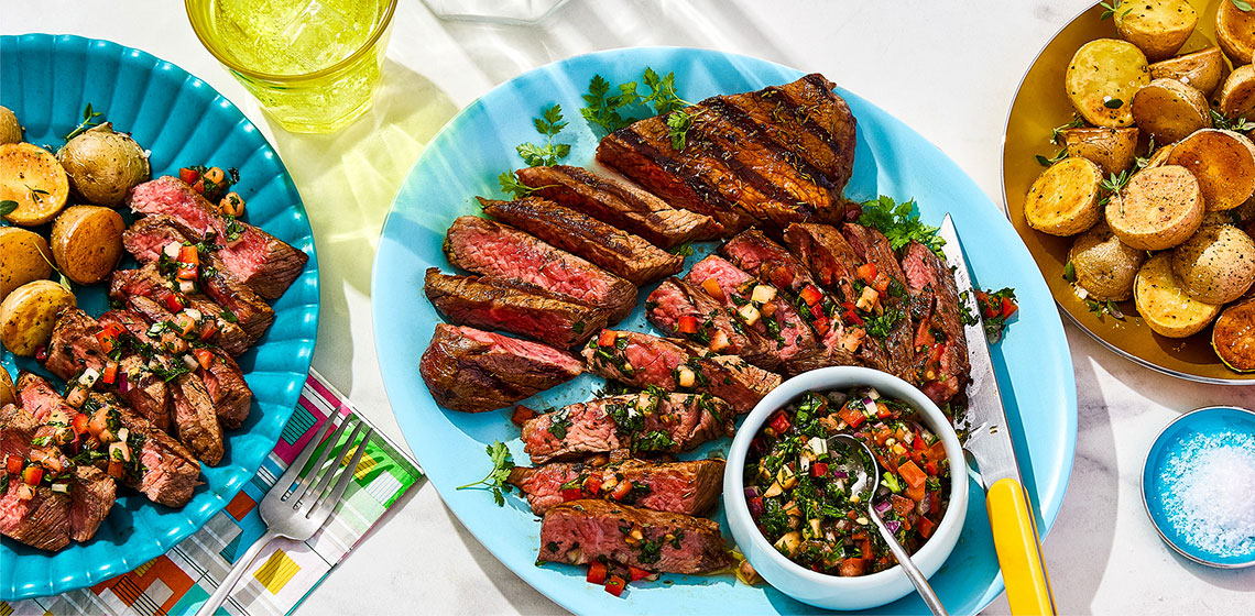 The plate in the centre has the tri tip steak sliced with the salsa on top and in a small bowl with two other plates surrounding it, one with potatoes and one with a combination of the sliced steak with salsa and more potatoes