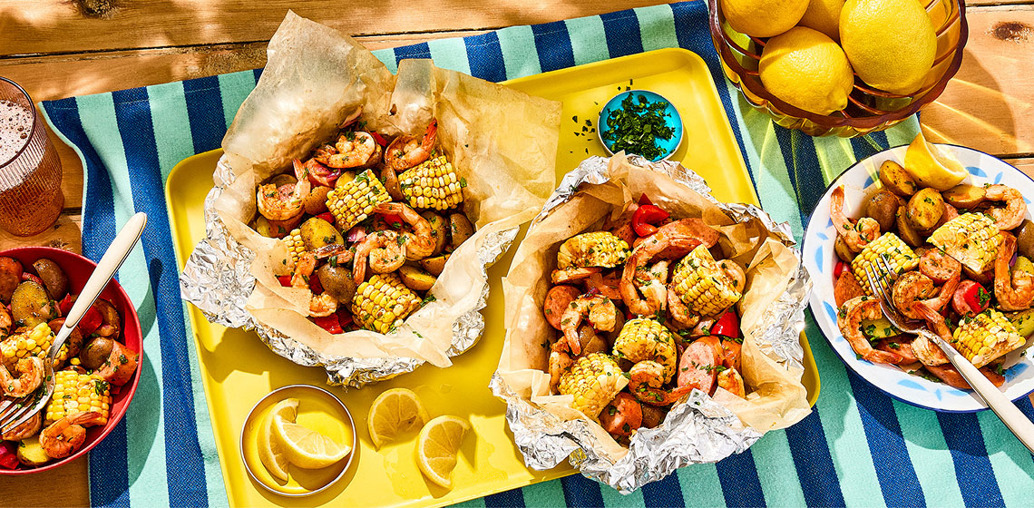 Overhead shot of shrimp boil aluminum packets with shrimp, corn, sausage and potato.