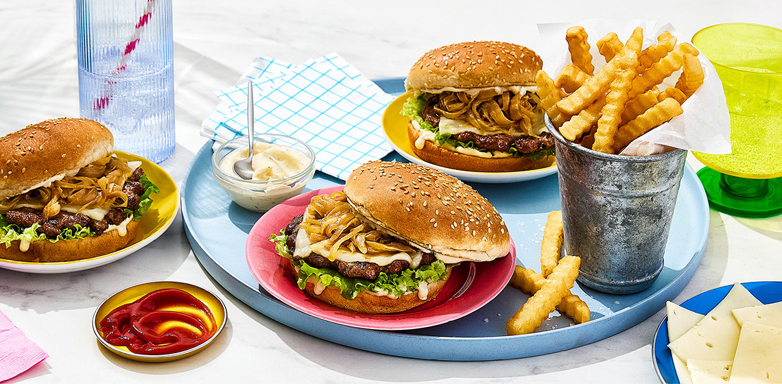 Three French onion smashed burgers with ketchup, mayo and crinkle fries on the side.