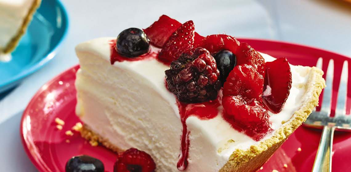  Ice cream pie with summer berries with a fork on a red plate.