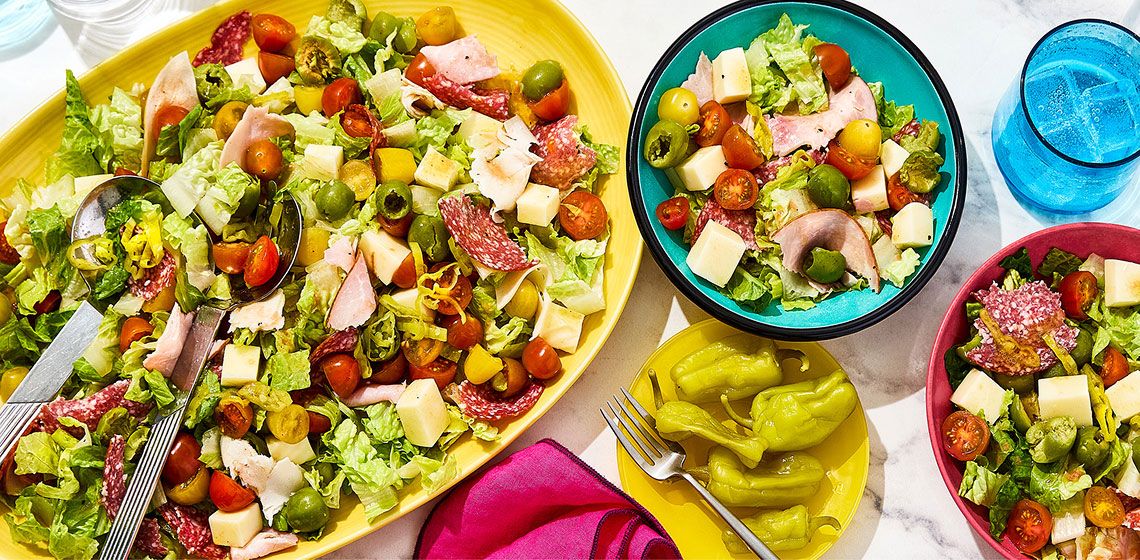 Italian grinder salad in a platter and 2 small bowls filled with salad beside it.