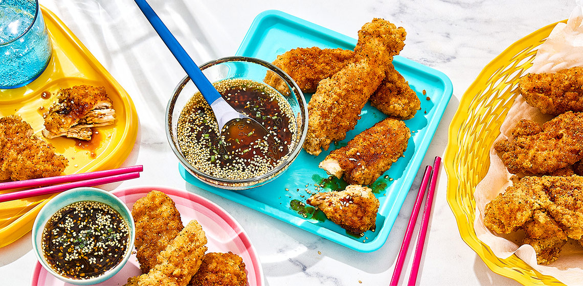 Korean chicken strips on turquoise plate with dip to the side.