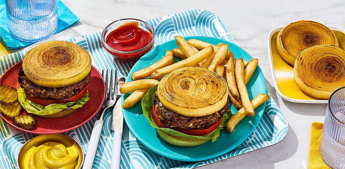 Mushroom and Mozzarella burger with a fried onion bun on a turquoise plate with a side of fries.