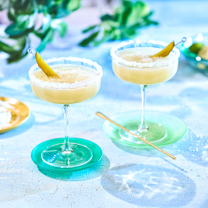 Pickle margarita on marble table top garnished with pickle slice