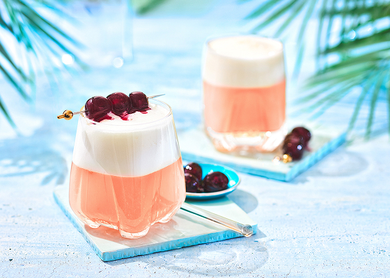 Two cherry sours in glasses garnished with 3 cherries.