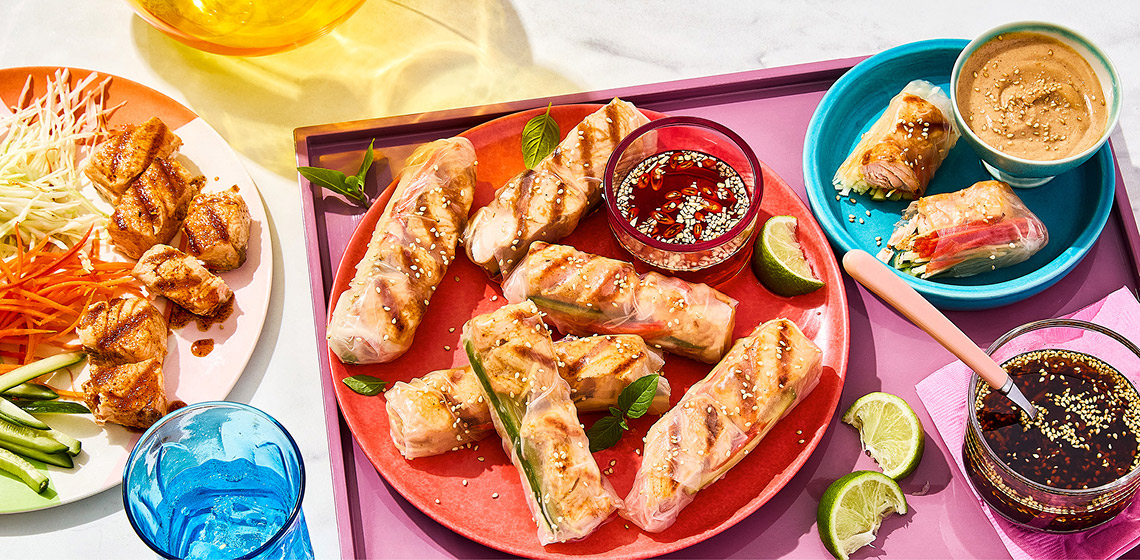 Salmon spiedini rolled in Vietnamese rice paper with veggies and dip on the side.