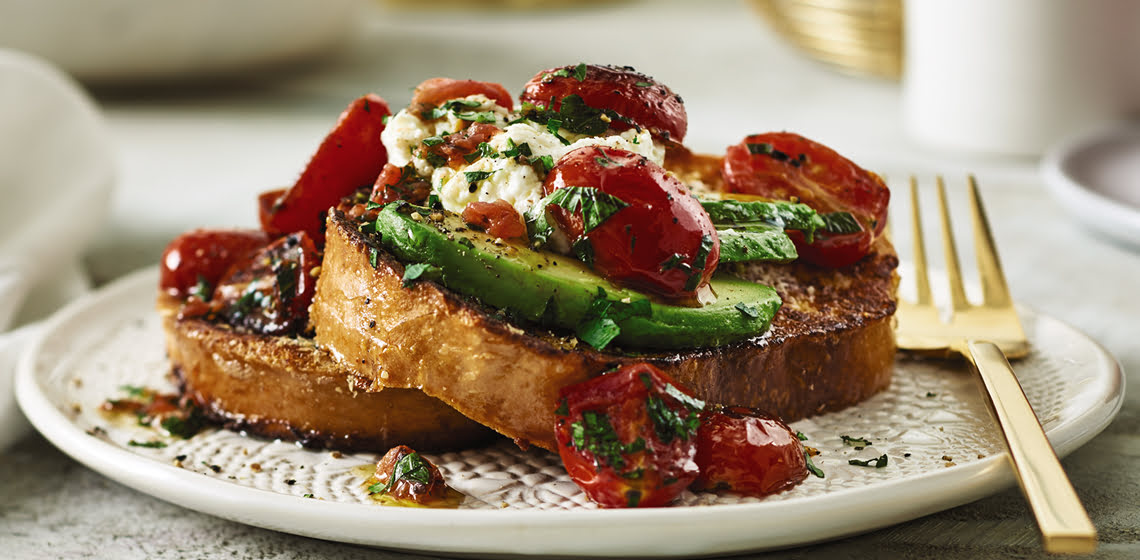 A plate of the Savoury French Toast with Caramelized Tomatoes and a fork.