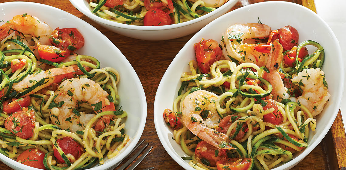 Three white bowls of Shrimp & Zucchini Zoodles on a wooden board.