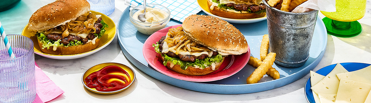 Three French onion smashed burgers with ketchup, mayo and crinkle fries on the side.
