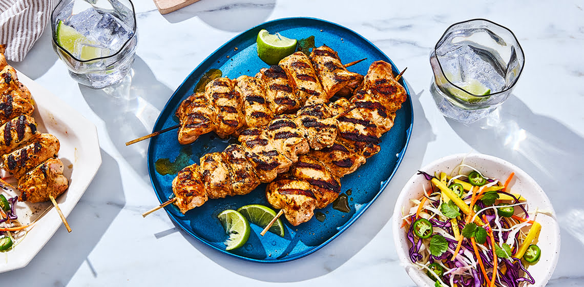 Overhead shot of grilled chicken kabobs with a side of mango slaw