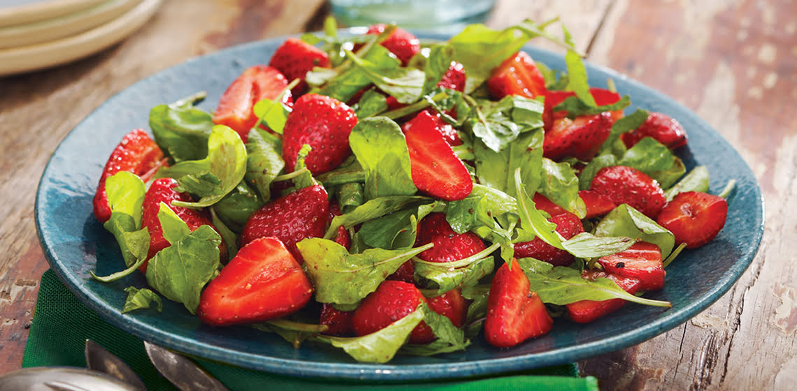Strawberry and arugula salad in turquoise bowl.