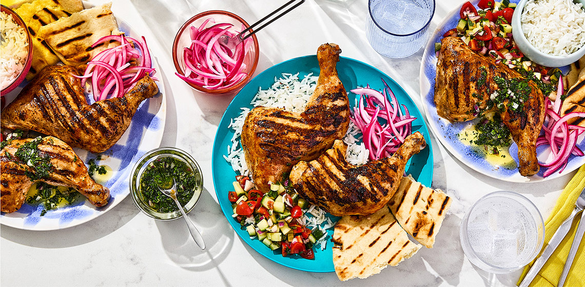Three plates all with Tandoori Chicken, rice, kachumber salad, naan bread or pickled red onions with a small bowl of the pickled red onions and another with mint chutney.